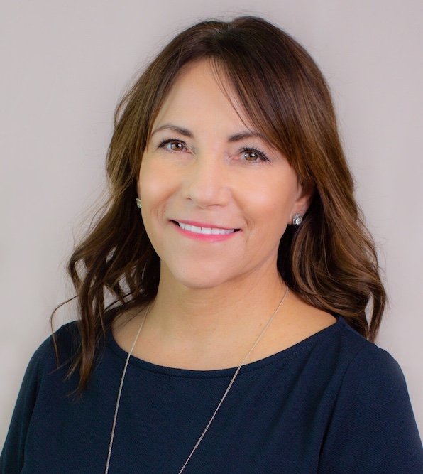 Suzanne, licensed esthetician and owner of Dermal 911, smiling in a navy top