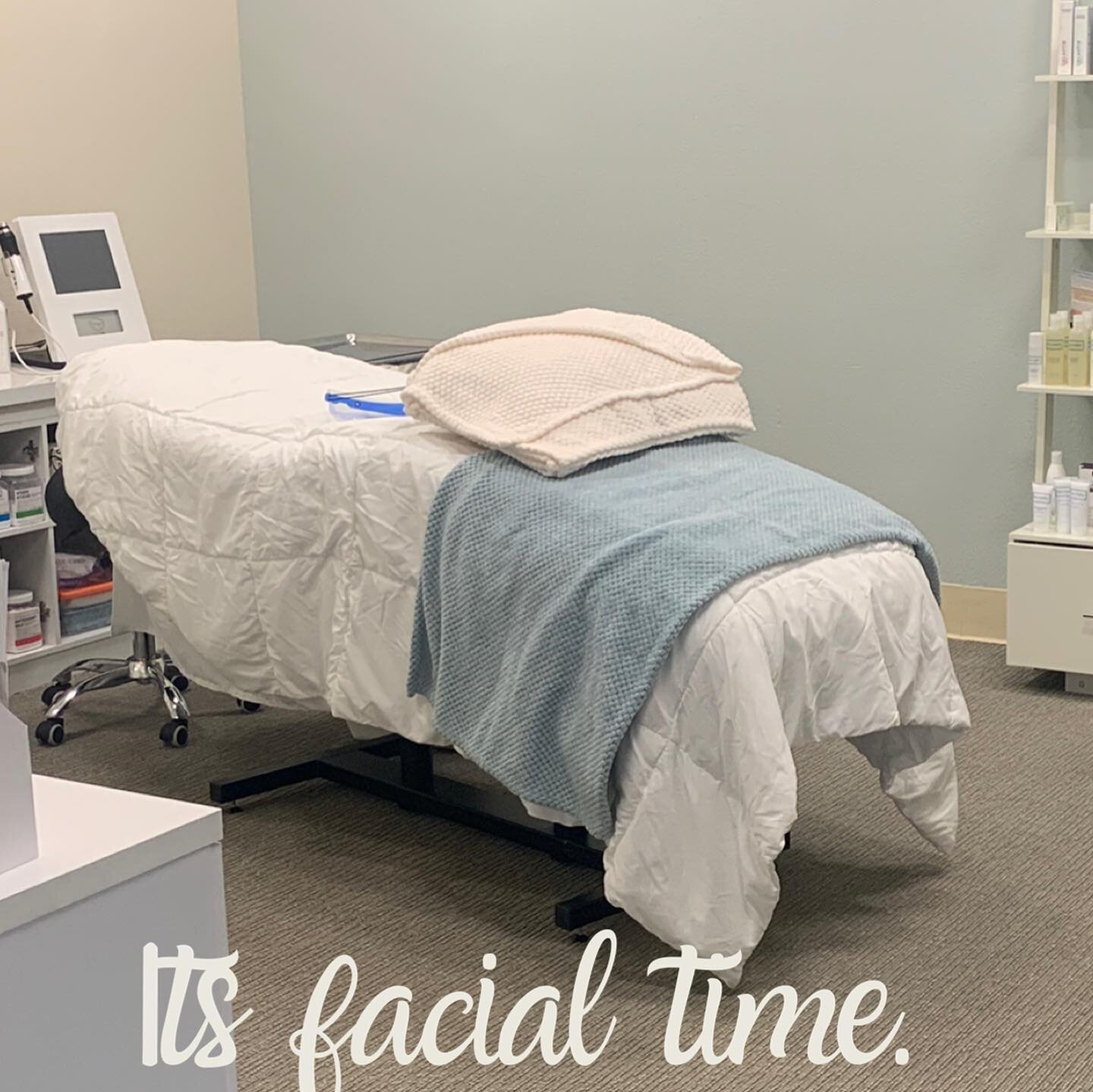 The Dermal 911 treatment room in Pleasanton: a facial bed with white linens and a blue throw, with the words “Its facial time.”